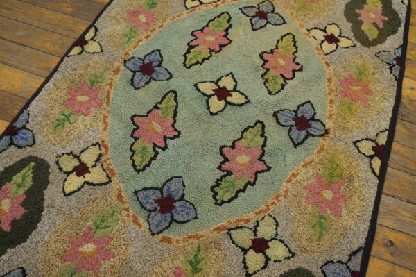 Floral textured rug with a teal center and pink, blue, and yellow flowers, lying on rustic wooden flooring.