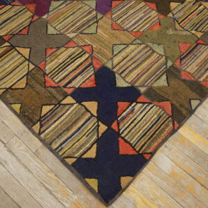 Earth-toned hooked rug with interlocking geometric patterns and multi-colored striped squares on light wood floors.