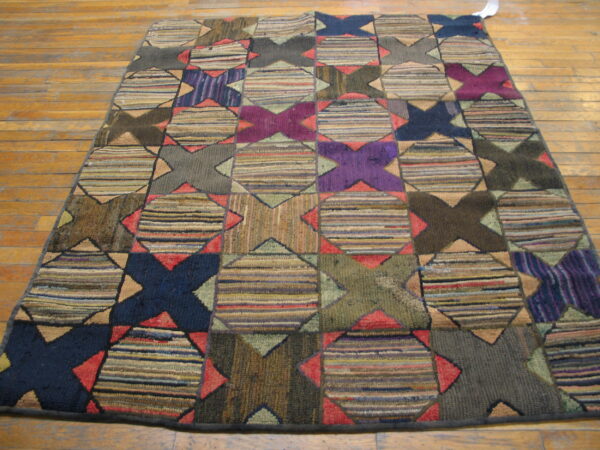 Textured, multi-color rug with repeating geometric star and striped block patterns on wood plank flooring.