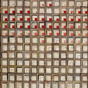 Textured rug with a grid pattern of nested L-shapes in mixed neutrals and scattered red accents.