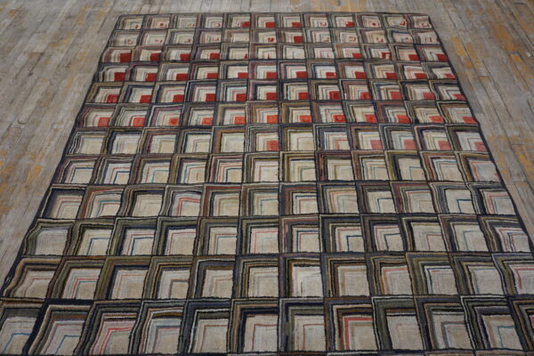 Textured rug featuring repeating multicolor squares with beige centers and navy borders on distressed wood planks.