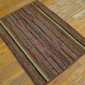 Striped rug in variegated brown, red, blue, and green on rustic light wood planks.