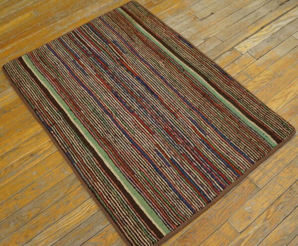 Striped rug in variegated brown, red, blue, and green on rustic light wood planks.