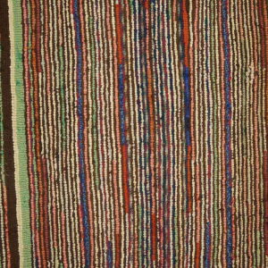 Textured rug with dense vertical stripes in brown, green, cream, red, and blue on wood flooring.
