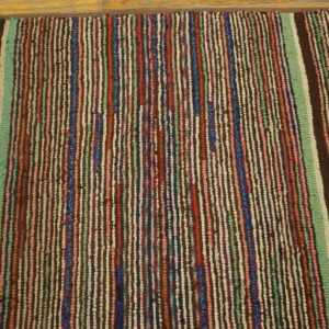 Textured rug with thin vertical stripes of brown, red, green, blue, and cream on light wood planks.