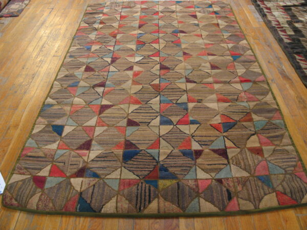 Brown, red, and blue patchwork geometric rug with a coarse texture is displayed on light wood flooring.