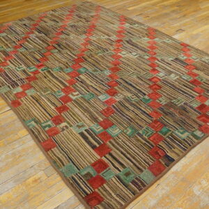 Earth-toned striped rug featuring a colorful red and teal block grid laid over worn hardwood floor.