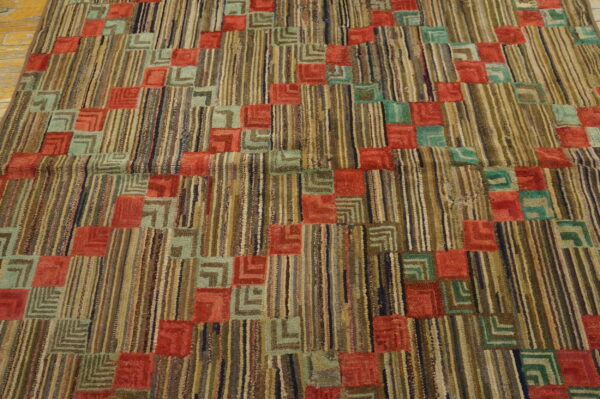 Textured rug with multicolored stripes and geometric squares in coral and teal green on wood floor.