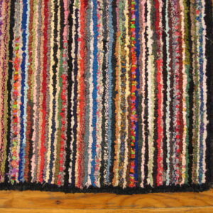 Highly textured multicolor rag rug with vertical stripes rests on wood plank flooring.