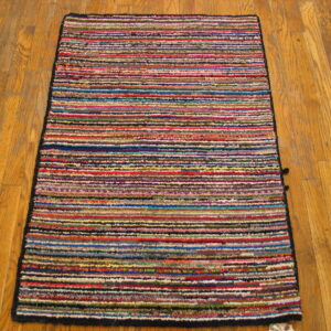 A textured rag rug with dense, multicolored horizontal stripes sits on natural hardwood flooring.