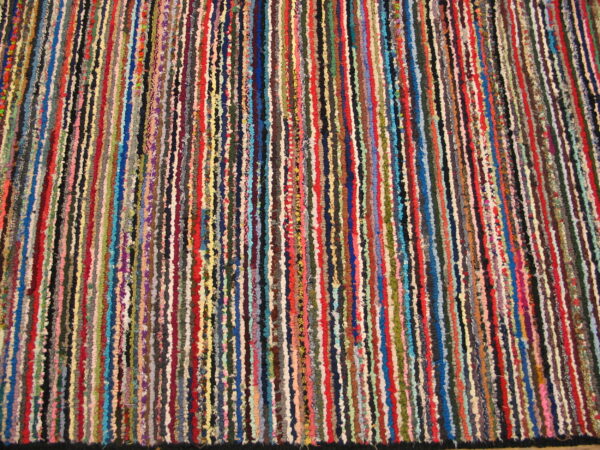 Textured rug displaying narrow vertical stripes in many colors, including red, blue, yellow, and green.