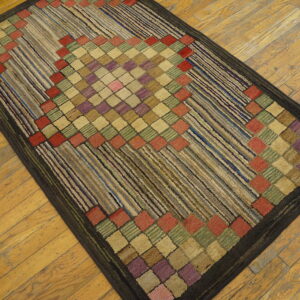 Textured, dark-bordered rug featuring multicolored square diamonds and diagonal linear stripes on wood.