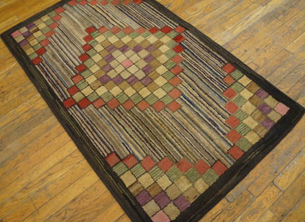 Textured, dark-bordered rug featuring multicolored square diamonds and diagonal linear stripes on wood.
