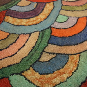 High-pile rug detail showing multicolored, curved, overlapping shapes defined by dark, stitched outlines.