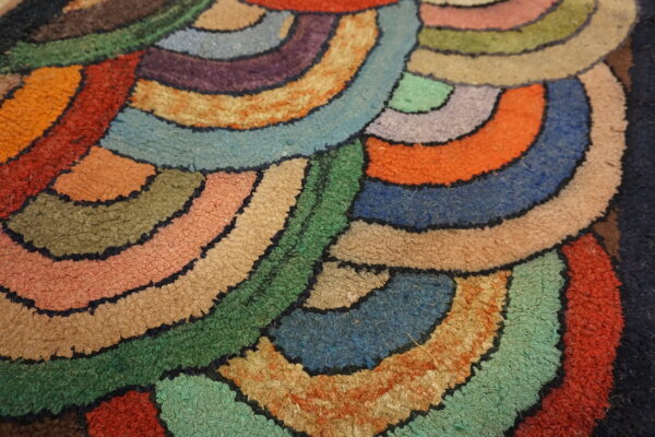 High-pile rug detail showing multicolored, curved, overlapping shapes defined by dark, stitched outlines.
