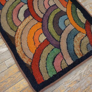 A multicolored hooked rug with overlapping circles in red, green, purple, and orange rests on distressed wood planks.