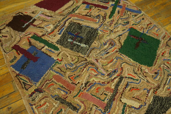 Highly textured patchwork rug featuring beige loops and blocks of blue, black, green, and maroon on wood planks.