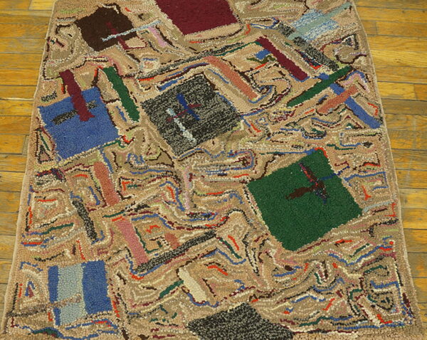 Highly textured abstract rug with blue, red, and green geometric blocks resting on warm wooden floor planks.