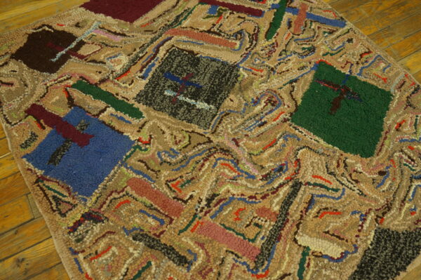 Close-up of a hooked texture rug with colorful geometric blocks and tan swirling patterns on wood flooring.