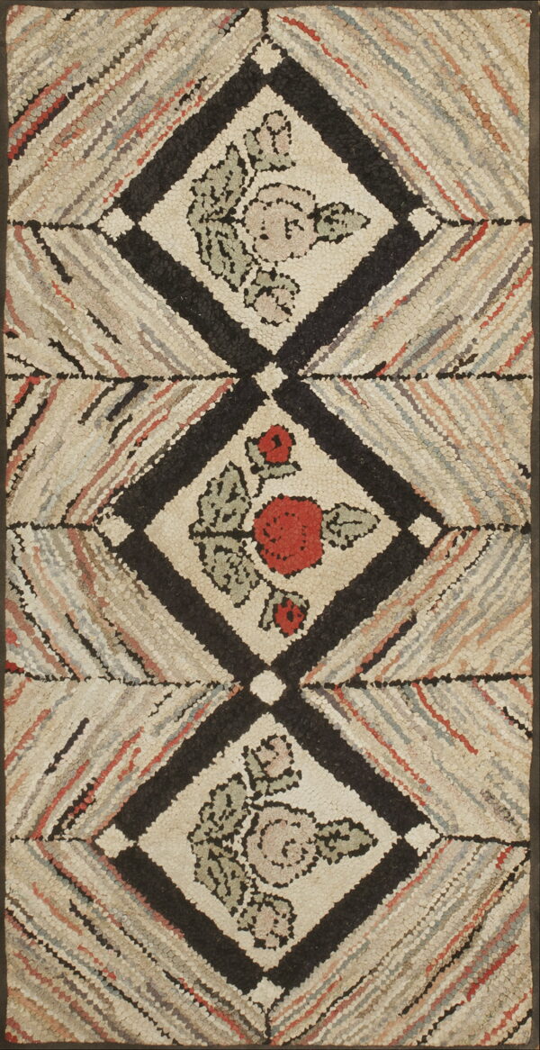 Hooked texture rug showing stacked black diamonds containing red and pink floral designs.