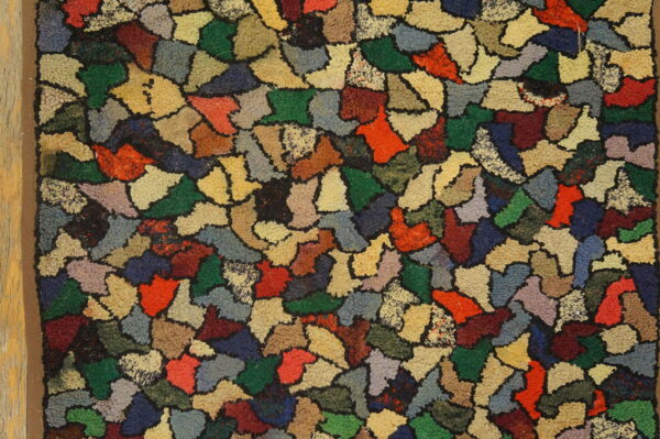 A heavily textured rug displays colorful abstract shapes in reds, greens, blues, browns, and yellows.