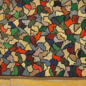 A multicolored, chunky rug features irregular color blocks outlined in black resting on light wood flooring.