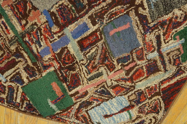 Close view of a shaggy, colorful rug with brown, blue, red, and green geometric patterning on wood.