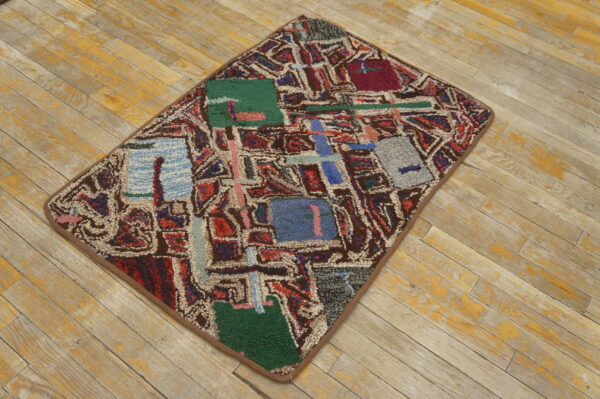 Textured rug with abstract blocks of red, blue, green, and brown geometric patterns rests on distressed wood planks.