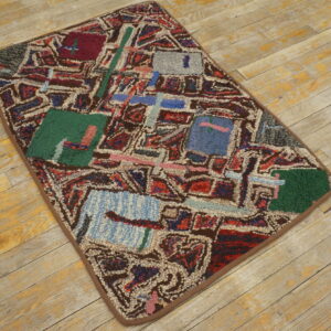 High-pile abstract rug in shades of green, red, blue, and brown rests on rustic light plank wood floor.