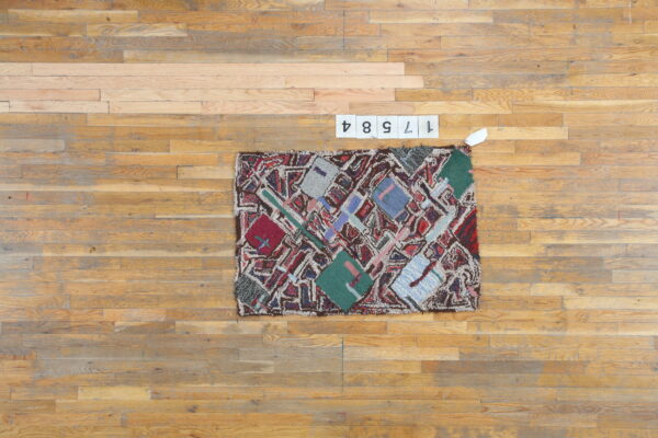 Shaggy, multicolored abstract rug with geometric shapes displayed on a light brown wood plank floor.