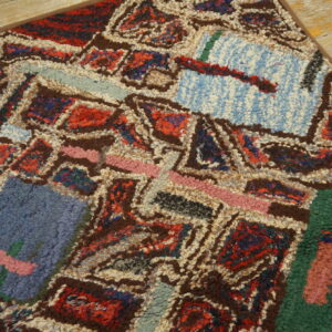 Shaggy, high-pile rug featuring multicolored abstract shapes rests on distressed wood flooring.
