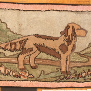 Pictorial hooked rug featuring a brown dog standing in a green and tan landscape with a textured pink border.