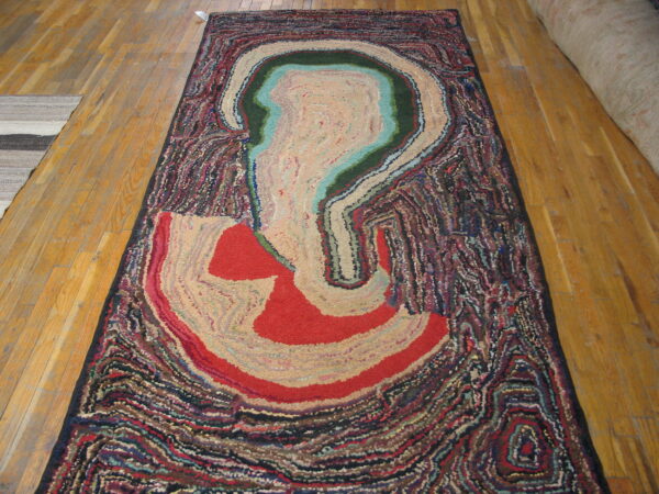 Multicolored rug with a dense texture and abstract striated pattern resembling an agate cross-section on wood planks.