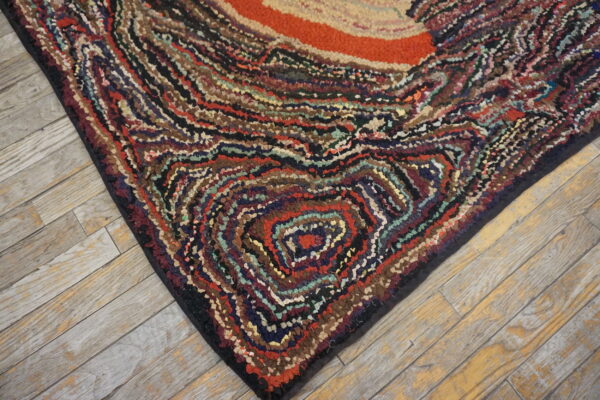 Chunky, high-textured multicolored rug with swirling stripes and an orange center on light wood planks.
