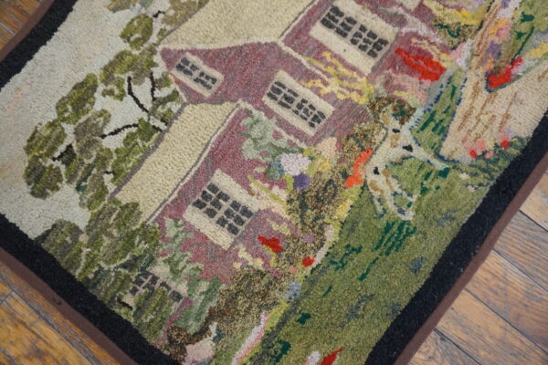 Multi-colored, hooked-style rug displaying a pictorial pattern of a burgundy house and lush green yard.