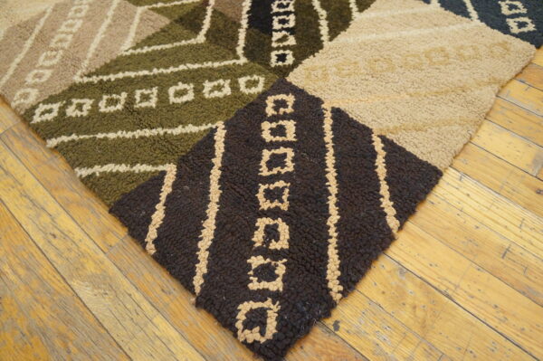 Geometric looped pile rug in brown, beige, and olive green resting on rustic wood flooring.