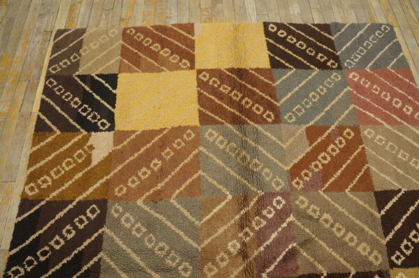 Geometric patchwork rug in various browns, yellow, and gray with a visible looped texture on wood floor.