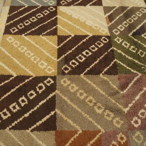 Earth toned textured rug featuring checkered blocks, diagonal stripes, and geometric shapes on wood floor.
