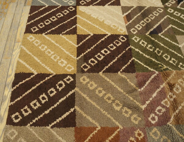 Earth toned textured rug featuring checkered blocks, diagonal stripes, and geometric shapes on wood floor.