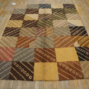Earth-toned high-pile rug displays a large checkerboard of squares filled with diagonal stripe patterns on distressed wood flooring.