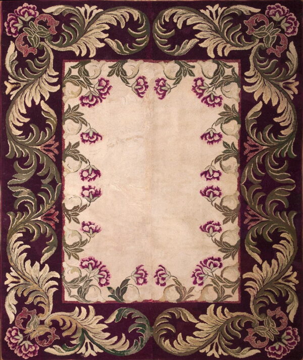 Burgundy and cream rug with a decorative border of green scrolling leaves and magenta floral accents.