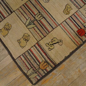 Beige and striped hooked rug with bear and tulip motifs rests on diagonally laid wood planks.