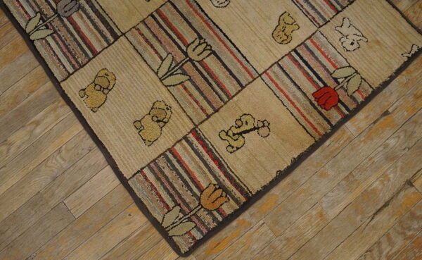 Beige and striped hooked rug with bear and tulip motifs rests on diagonally laid wood planks.