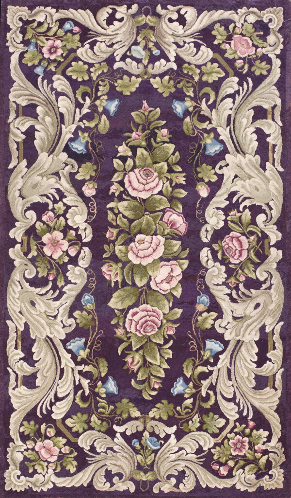 Ornate purple rug with a sculpted floral pattern featuring pink roses, green leaves, and cream baroque scrolls.