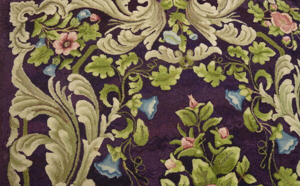 Plush floral rug with pink, blue, and green motifs against a rich purple cut-pile background.