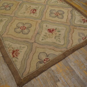 Hooked beige rug with floral panels in muted pink, red, and green on distressed wood flooring.