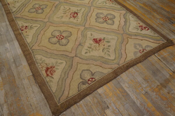 Hooked beige rug with floral panels in muted pink, red, and green on distressed wood flooring.
