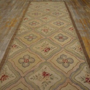 Textured beige runner with a floral diamond pattern in pastel tones rests on distressed hardwood flooring.