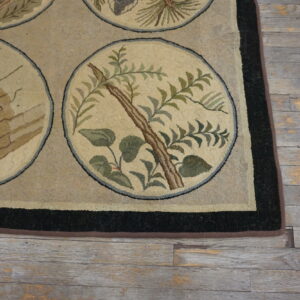 Tan and black border rug featuring circular woodpecker and foliage designs on rustic gray flooring.