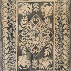 Textured hooked rug displaying dense beige and pink floral patterns and a central diamond on a dark, variegated field.